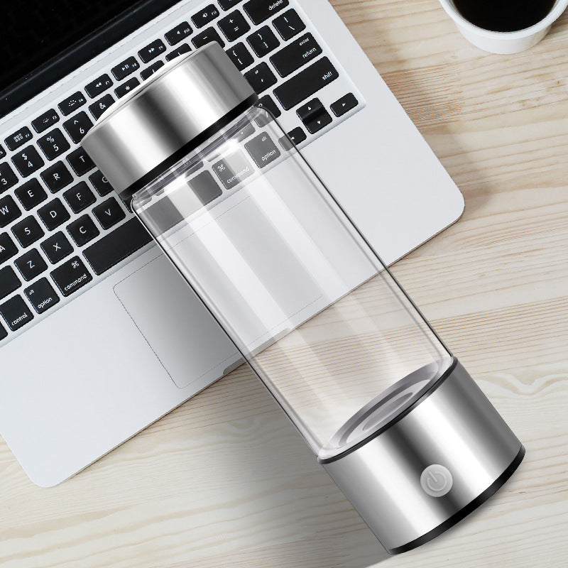 Clear and silver water bottle on a desk with a laptop and coffee cup.