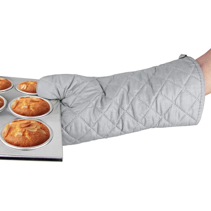 Person wearing an oven mitt holding a tray of muffins.