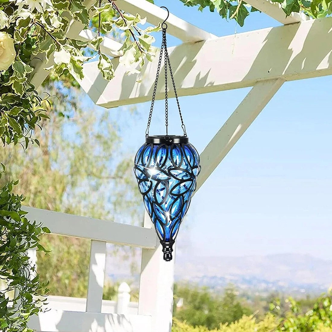 Blue glass hanging lantern with intricate design in a garden setting