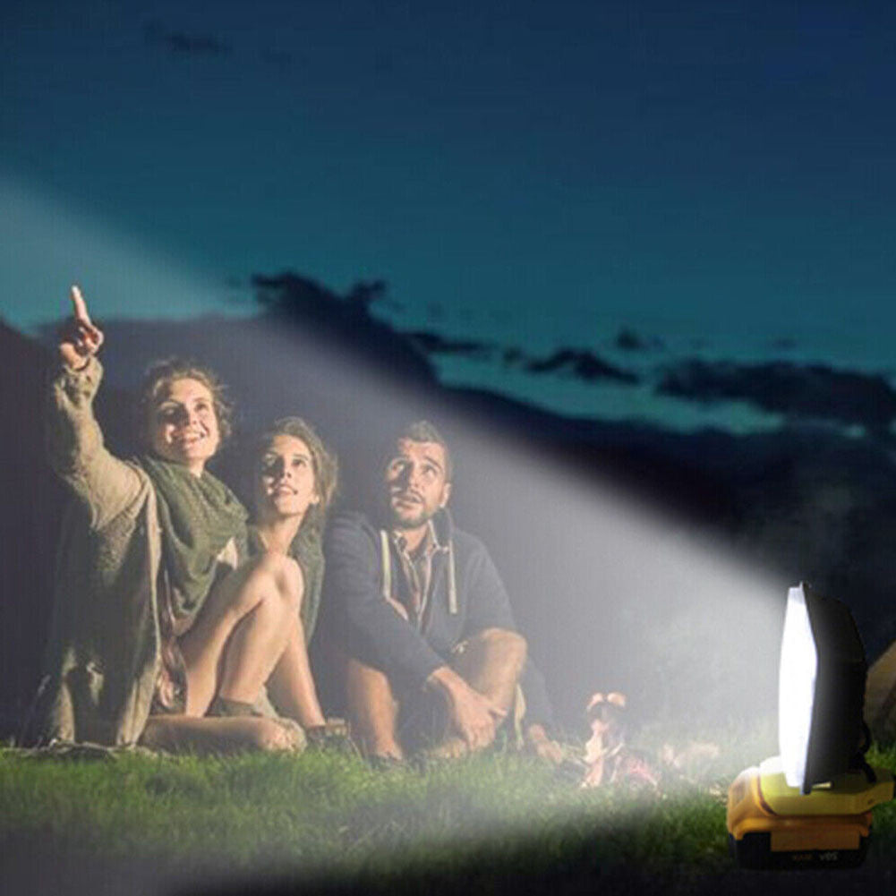 Three people sitting by a campfire at night, with a flashlight beam directed towards them.
