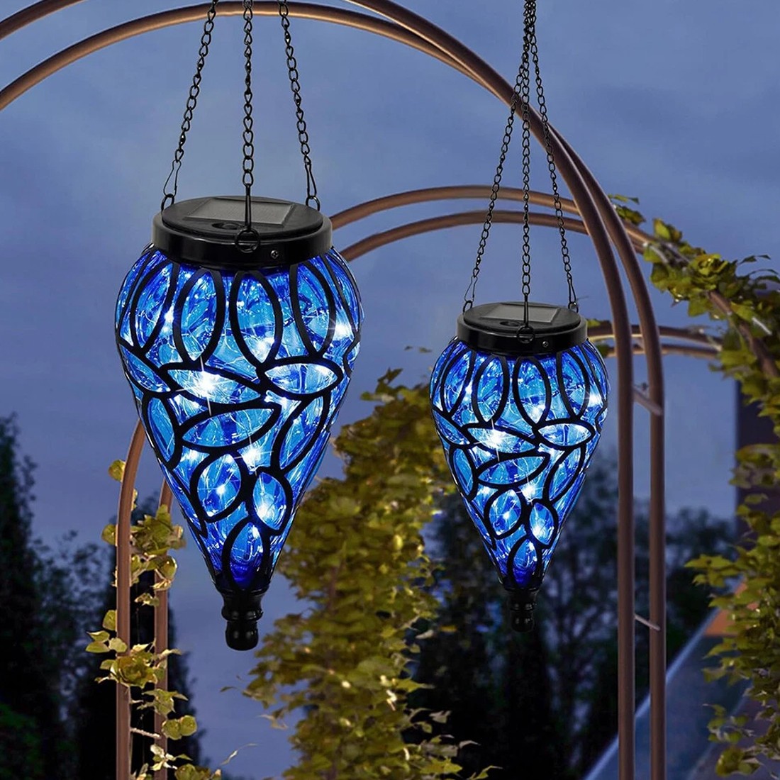 Two blue hanging solar lights with intricate designs against a dark sky.