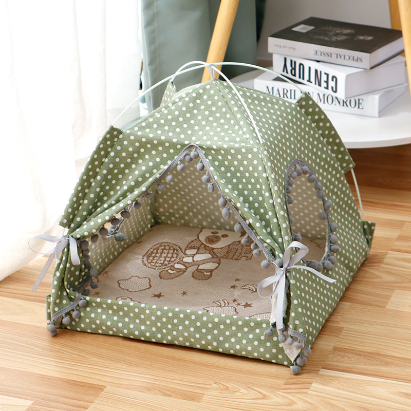 Green polka dot pet tent on a wooden floor with books in the background