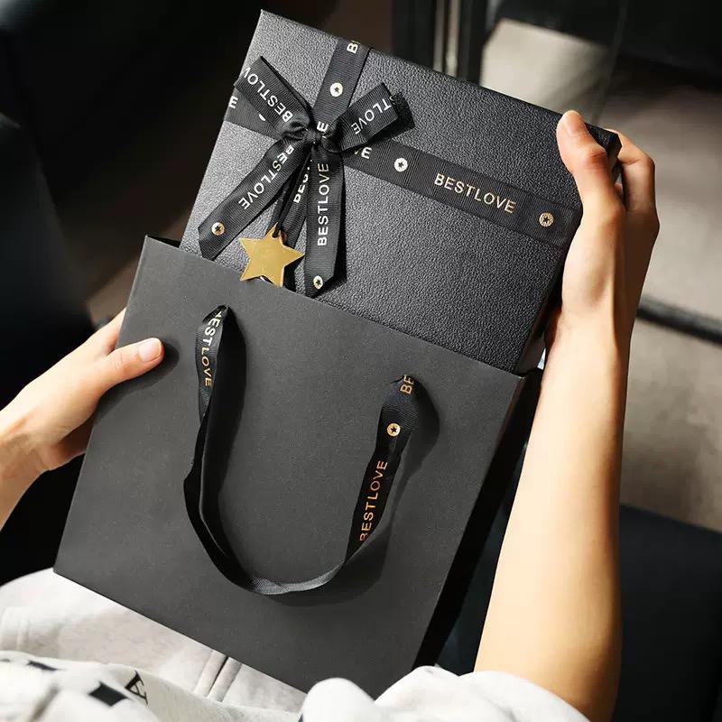 Person holding a black gift box with 'BESTLOVE' branding and ribbons.