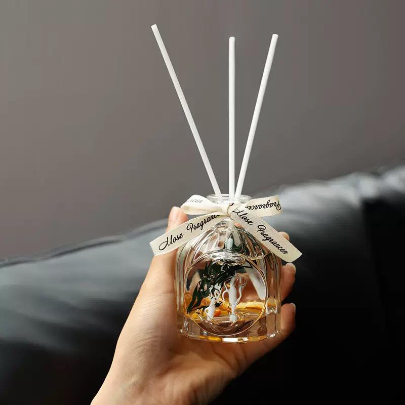 Hand holding a diffuser with reeds against a dark background