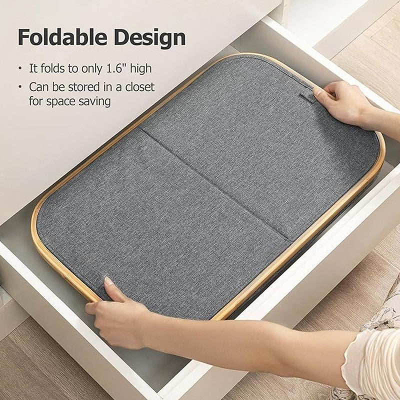 Foldable gray mat with wooden border being folded by a person, shown on a white surface.